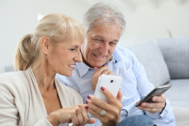 30222413 - senior couple at home using smartphone