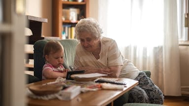 Elderly woman and baby enjoying together time indoors.